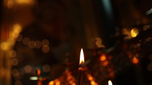 The soft light of a candle in the church. Slow motion