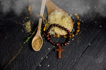 crucifix rosary and rice, Christian cross necklace on dark background - as a symbol of the...