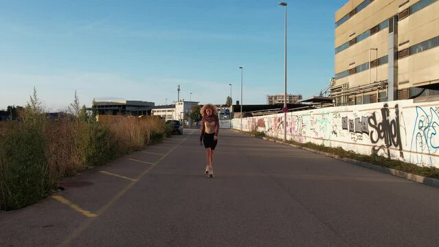 young curly blonde woman doing roller skating in an burban area 