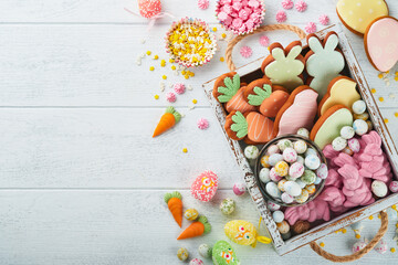 Sweet Easter concept. Sweet Easter kids holiday assortment marshmallows rabbit, chocolates easter eggs, candies, bunny, snacks  on white wooden background. Flat lay Easter decoration idea. Mock up.