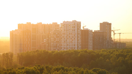 Construction cranes and buildings at sunset.