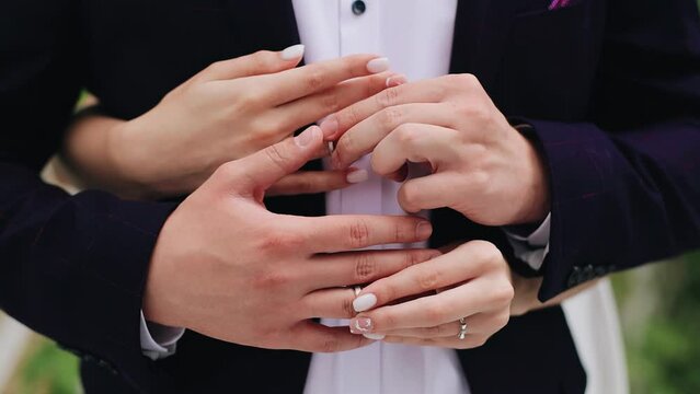 The newlyweds hold wedding rings in their hands and put them on. Close-up shooting of hands
