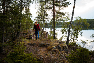 Man walking in forest by lake a summer evening