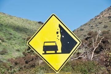 Caution sign beware falling rocks symbol yellow black blue sky Malibu Caliornia