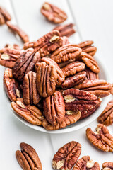 Peeled pecan nuts in bowl on white table.