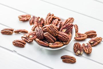 Peeled pecan nuts in bowl on white table.