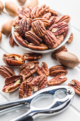 Peeled pecan nuts in bowl on white table.