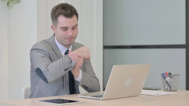 Young Businessman with Wrist Pain Working on Laptop