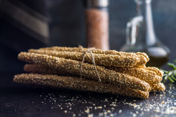 Italian grissini bread sticks with sesame seeds on kitchen table.