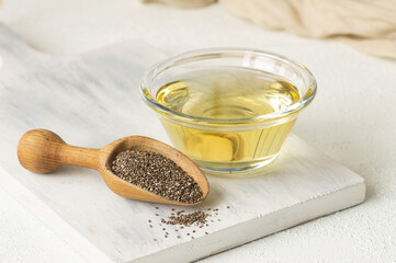 Glass bottle of Chia oil with Chia seeds ( Salvia Hispanica ) in wooden shovel on rustic background