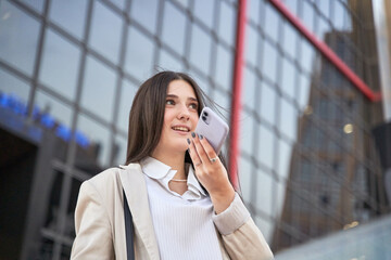 caucasian woman sending a voice message with her smart phone. She is in financial district