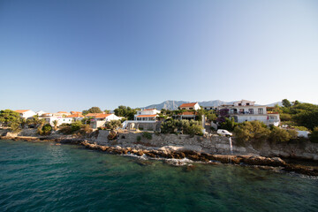 sea ​​view of the coast of the Croatian island of Hvar with typical buildings during summer with blue sky - obrazy, fototapety, plakaty