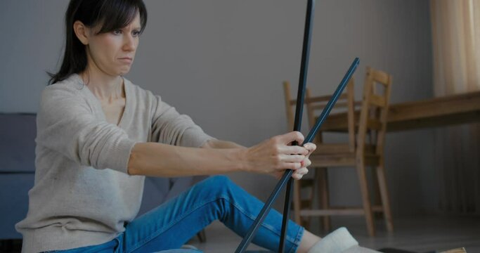 Woman assembles flat pack shelf in home living room