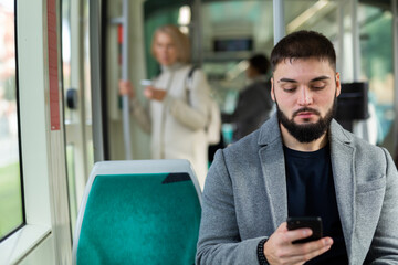 Portrait of male passenger using mobile phone in tram. High quality photo