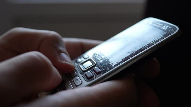 Close-up male hands are using an old push-button mobile phone from the past. Technology development concept.