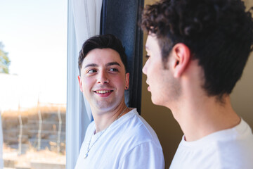 Gay couple sharing a special moment in the morning by the window. Homosexual romantic tenderness.