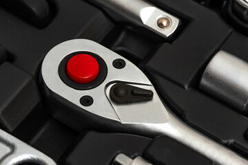 Chrome vanadium steel ratchet wrench with switch and red button in tool box.