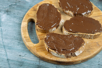 Chocolate cream on the sliced bread above blue background
