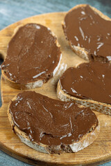 Chocolate cream on the sliced bread above blue background