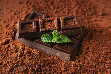 Dark and milk chocolate with nuts on a dark background sprinkled with cocoa powder.