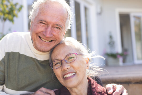 Happy senior diverse couple embracing and smiling in garden