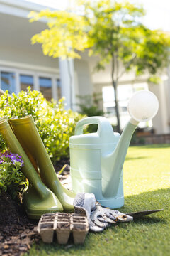 Close up of watering can and rain boots in garden