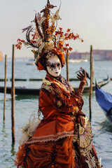 Venetian carnival mask in orange costume, traditional carnival in Venice, Italy, person in costume.