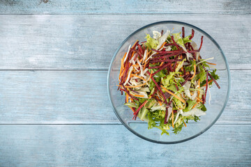 Fresh vegetables salad in the bowl above dark moody blue background