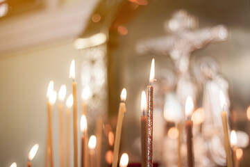 wax candles in the temple next to the cross, the front and back backgrounds are blurred with a...