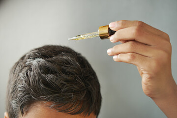  young men applying essential oils on his hair 