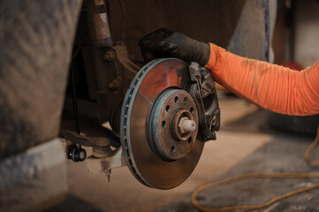 Car brake part in the garage, car brake disc without wheels. Car suspension. Current car repair - obrazy, fototapety, plakaty