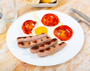 Fried eggs with tomato served with homemade meat sausages