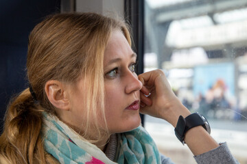 Junge Frau im Zug blickt nachdenklich aus dem Fenster