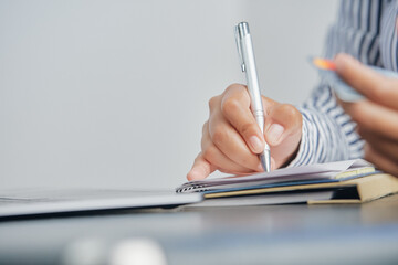 Business woman calculating monthly expenses, managing budget. Woman sitting at table using laptop and cell phone to calculate tax refund, working in office with laptop on table, finance concept