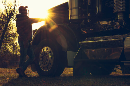 Semi Truck Driver in Front of His Vehicle During Scenic Sunset