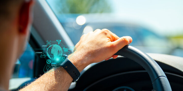 A close up of a man's hand in car with smartwatch showing futuristic web icons