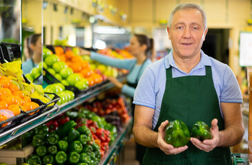 male seller of vegetable shop chooses fresh and ripe onion for regular customer