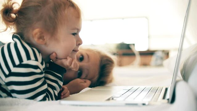Little girls watch movie on a laptop together