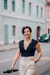 Woman wearing beige pants and a black lace top walking in the city street