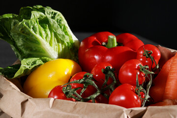 close up of fresh vegetables in eco paper bag, dark background 