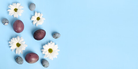 Fototapeta na wymiar Beautiful painted Easter eggs and daisy flowers on light blue background with space for text