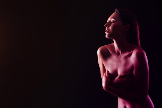 Toned portrait of naked young woman on black background with space for text
