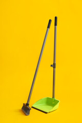 Cleaning broom with dustpan on yellow background