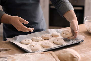 Male baker making buns at table in kitchen, closeup