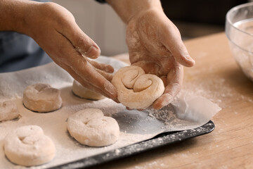 Male baker making buns at table in kitchen, closeup