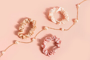 Silk scrunchies and necklace on pink background