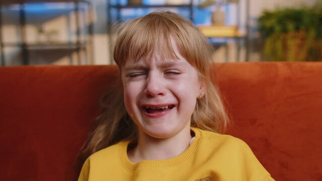 Close-up portrait of upset punished child little girl kid crying with tears flowing down on cheeks at home. Quarrel, fear abuse, bullying, education test exam fail at school. Family violence concept