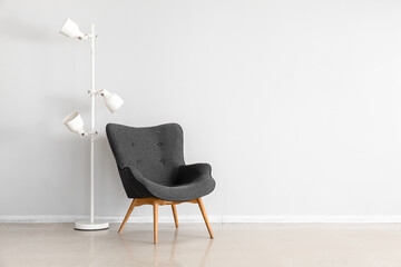 Stylish grey armchair and lamps near white wall - obrazy, fototapety, plakaty