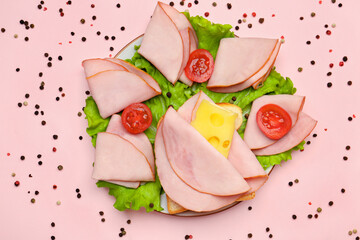 Plate with tasty slices of ham, cheese, lettuce and tomatoes on pink background