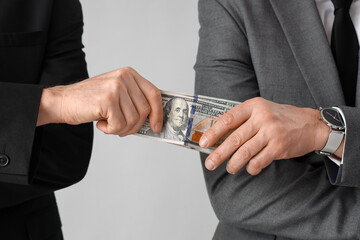 Businessman giving bribe on grey background, closeup